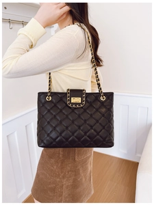 Détail du sac à bandoulière en cuir matelassé noir avec chaîne dorée et fermoir rotatif