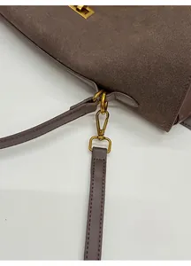 Detail of dark brown suede tote featuring gold metal lobster clasps and a detachable strap