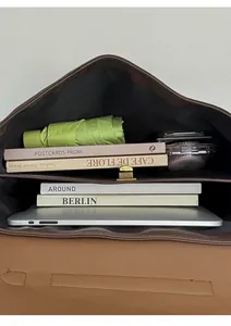 Top view of deep brown leather bag showing dual compartments with a laptop and daily items