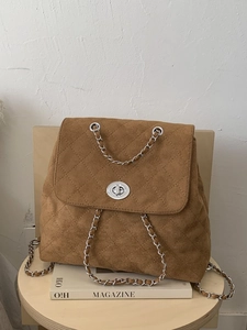 Sac à dos vintage en daim matelassé marron avec bretelles en chaîne argentée sur tabouret