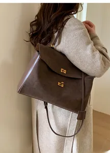 Detail view of coffee suede and leather tote bag featuring gold metal turn-buckle closures