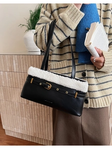 Detail of black leather shoulder bag with white faux fur trim and gold buckle accent