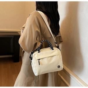 Close-up of cream crossbody bag with woven handle and adjustable wide shoulder strap