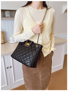 Détail du sac bandoulière noir matelassé avec chaîne dorée et fermoir pivotant chic