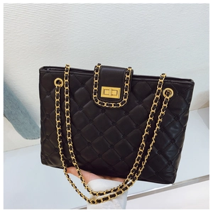 Détail d'un sac à bandoulière matelassé noir avec chaîne dorée et fermoir pivotant chic
