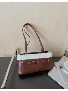 Detail of brown shoulder bag with white faux shearling trim and golden buckle strap