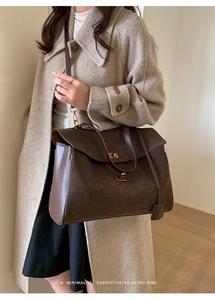 Detail of dark brown retro tote bag showing leather texture and gold buckle on a model