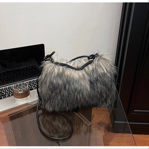 Detail of fuzzy faux fur shoulder bag with grey gradient and leather strap in office setting