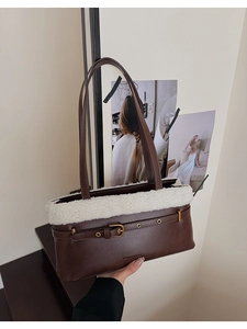 Detailed shot of dark brown leather shoulder bag with white faux fur trim and gold buckle
