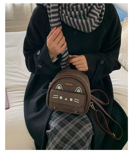 Detail of a mini cat-themed brown backpack with cute mint ears and gold logo accents