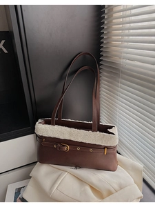 Close-up of deep brown leather shoulder bag with plush beige wool trim and metal buckles