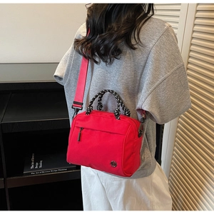 Red waterproof nylon crossbody bag featuring braided rope handles and wide shoulder strap