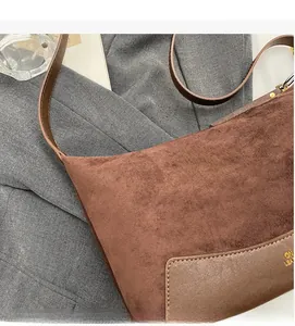 Detailansicht der braunen Wildleder-Schultertasche mit goldener Logo-Prägung