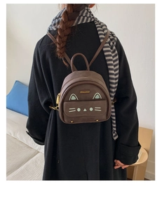 Mini brown cat-shaped leather backpack featuring cute green facial details and slim straps