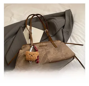 Detailed texture of brown vintage shoulder bag with plush bear charm and woven cord