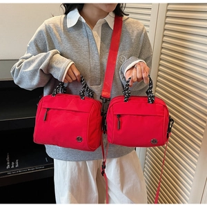 Close-up of red canvas handbag with braided handles and metal M logo detail