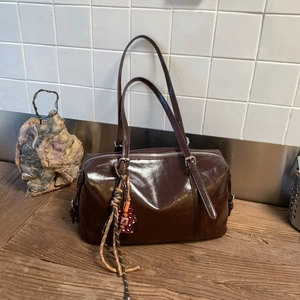 Detailed macro view of glossy dark brown faux leather texture and vintage tote strap