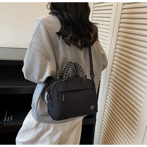 Detailed view of black nylon crossbody bag with woven handle and circular M logo on a model
