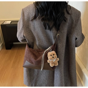 Detailansicht der braunen Wildleder-Patchworktasche mit einem Plüschbär-Anhänger an einem Model