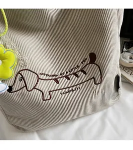 Detail of dachshund embroidery on beige corduroy tote with a floral charm