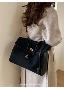 Detail of minimalist retro black tote with matte texture and golden twist lock
