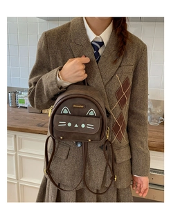 Detail shot of mini brown cat-themed backpack featuring leather straps and zipper closure
