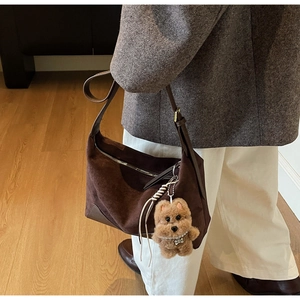 Detail der dunkelbraunen Wildleder-Schultertasche mit niedlichem Plüschhund-Anhänger