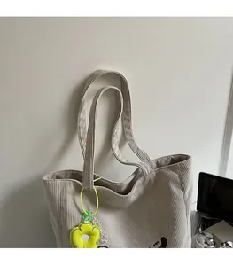Close-up of corduroy tote bag straps and a decorative yellow flower charm detail
