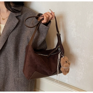 Detailansicht einer braunen Wildleder-Beuteltasche mit Plüschbär-Anhänger und Reißverschluss