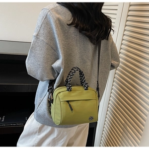 Olive green crossbody bag with woven handles and metallic M logo shown on a model