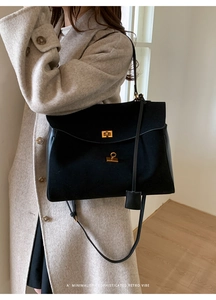 Detail of a vintage black suede tote bag with gold twist-lock and leather pendant