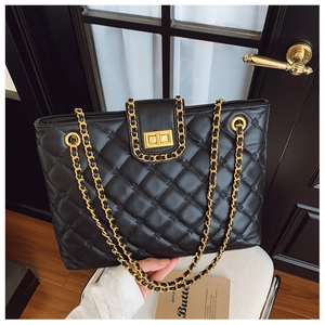 Détail de la texture matelassée du sac cabas noir avec garniture dorée élégante