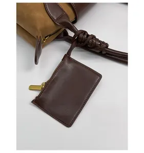 Close-up of brown leather shoulder bag with a matching mini coin purse keychain