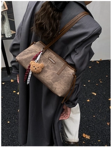 Sac bandoulière marron vintage avec charm ours porté avec un blazer gris chic