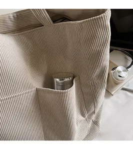 Detail of beige corduroy tote bag featuring a practical external pocket for water bottles