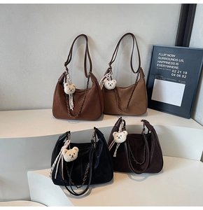 Detail of minimalist dumpling bags in four colors with chains and bear charms
