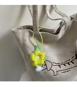 Detail of yellow flower plush pendant on corduroy tote bag with green lanyard