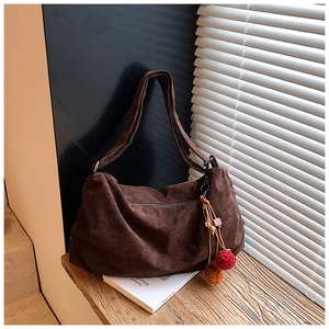 Detail of dark brown corduroy hobo bag featuring plush pom-poms and beaded charm decor