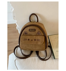 Detail of a brown suede cat-ear backpack with embroidered whiskers on a white textured sofa