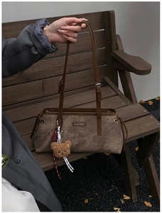 Détail du sac bandoulière vintage marron foncé avec plaque métal et pendentif ours en peluche