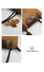 Detail view of khaki suede tote bag with brown leather handles and plush charm accessory