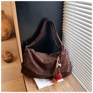 Detailed macro view of dark coffee suede tote texture with ethnic tassel and bead charm