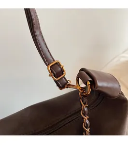 Close-up of vintage gold buckle and chain strap detail on a dark brown leather bag