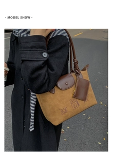 Detail of caramel suede hobo bag with cartoon embroidery and leather charm accessory