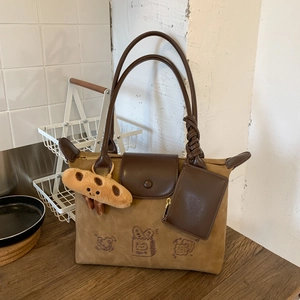 Detail of high-end hobo bag with bread embroidery, plush charm and textured fabric