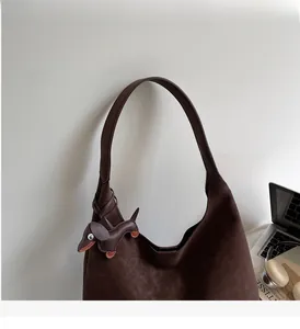 Detail of dark brown hobo bag with a decorative dachshund dog charm and comfortable strap
