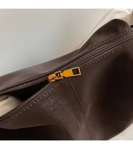 Macro shot of smooth gold-tone zipper hardware and stitching on brown leather bag
