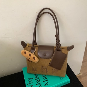 Detail of suede patchwork tote bag with cartoon illustration and plush toast charm accessory