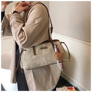 Detailed shot of casual shoulder bag featuring beige faux leather and brown teddy bear charm