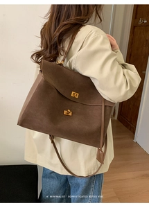 Detail of dark brown suede tote bag with metal twist lock and minimalist retro vibe